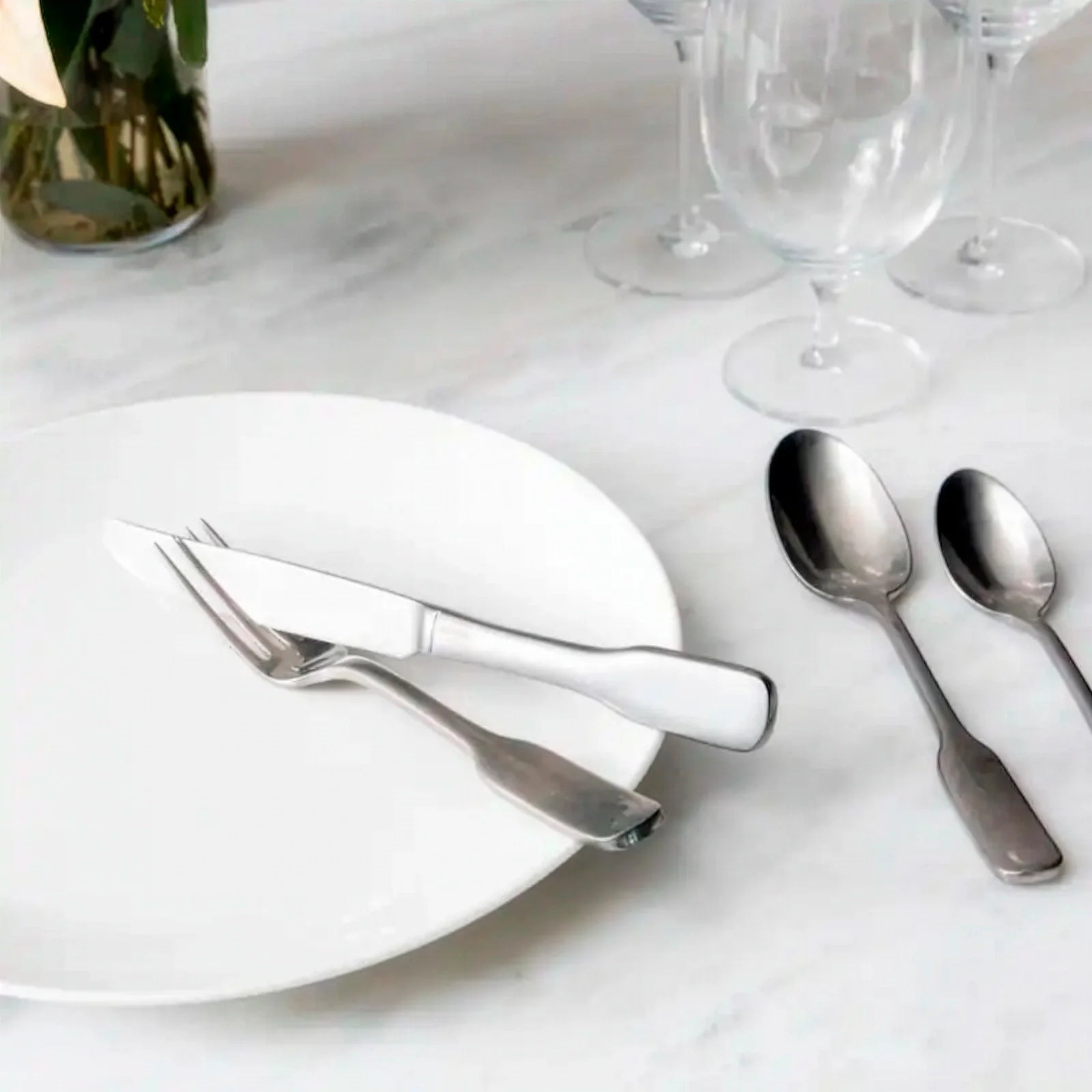 Montaje de mesa sofisticado y de estilo elegante en el restaurante de un hotel servido con la cubertería profesional Ashton Antiqued de Fortessa.