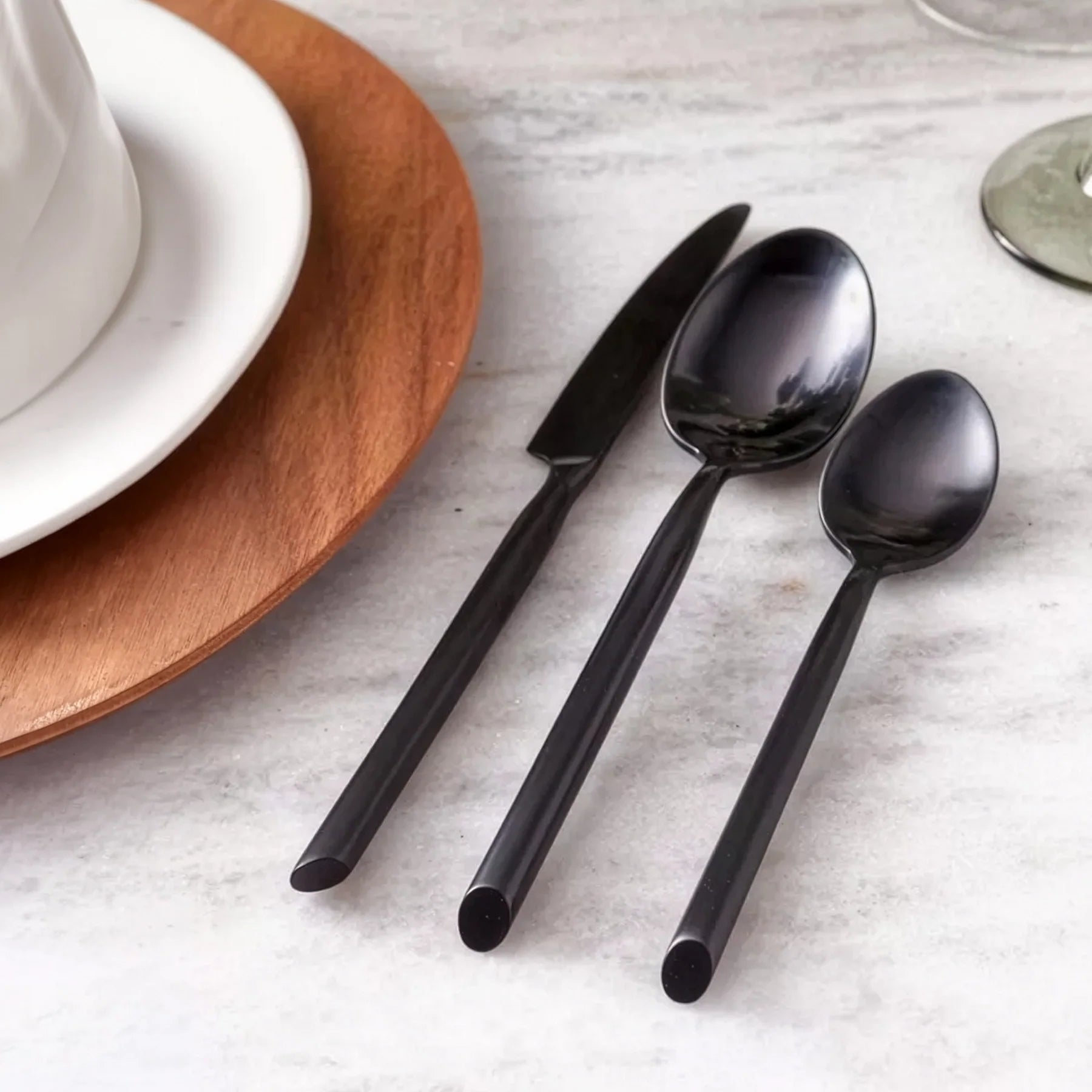 Montaje de mesa contemporáneo y de estilo minimalista en el restaurante de un hotel servido con la cubertería negra Capri Brushed Black de Fortessa.