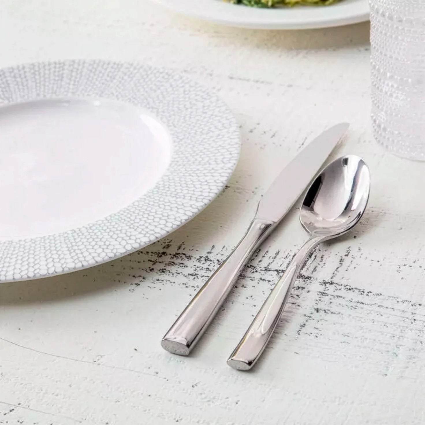 Set de cubiertos de la colección Lucca de Fortessa en acero inoxidable pulido espejo sobre una mesa de restaurante.