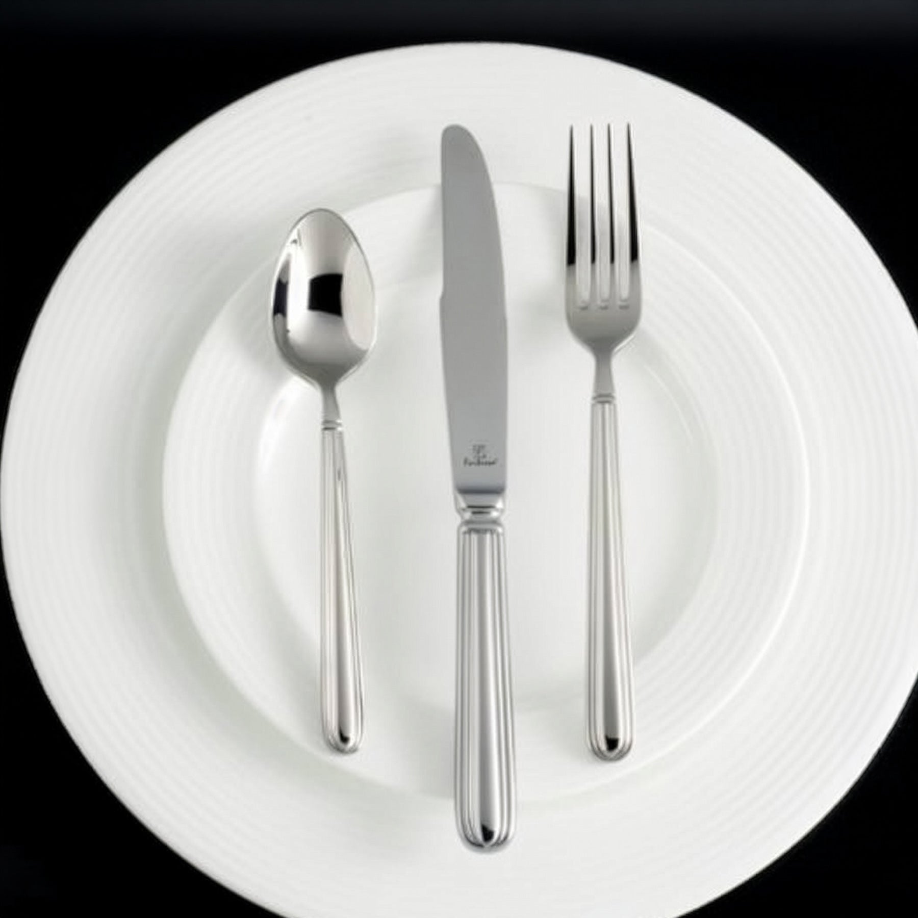 Set de cubiertos de la colección Metropolitan de Fortessa de diseño geométrico sobre una mesa de estilo industrial.