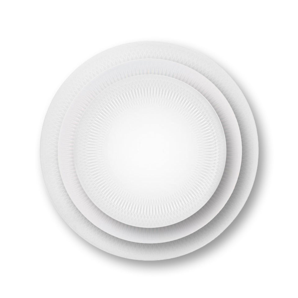 Platos de porcelana premium de la colección Utopia de Vista Alegre con su característico relieve geométrico tridimensional sobre un mantel minimalista.