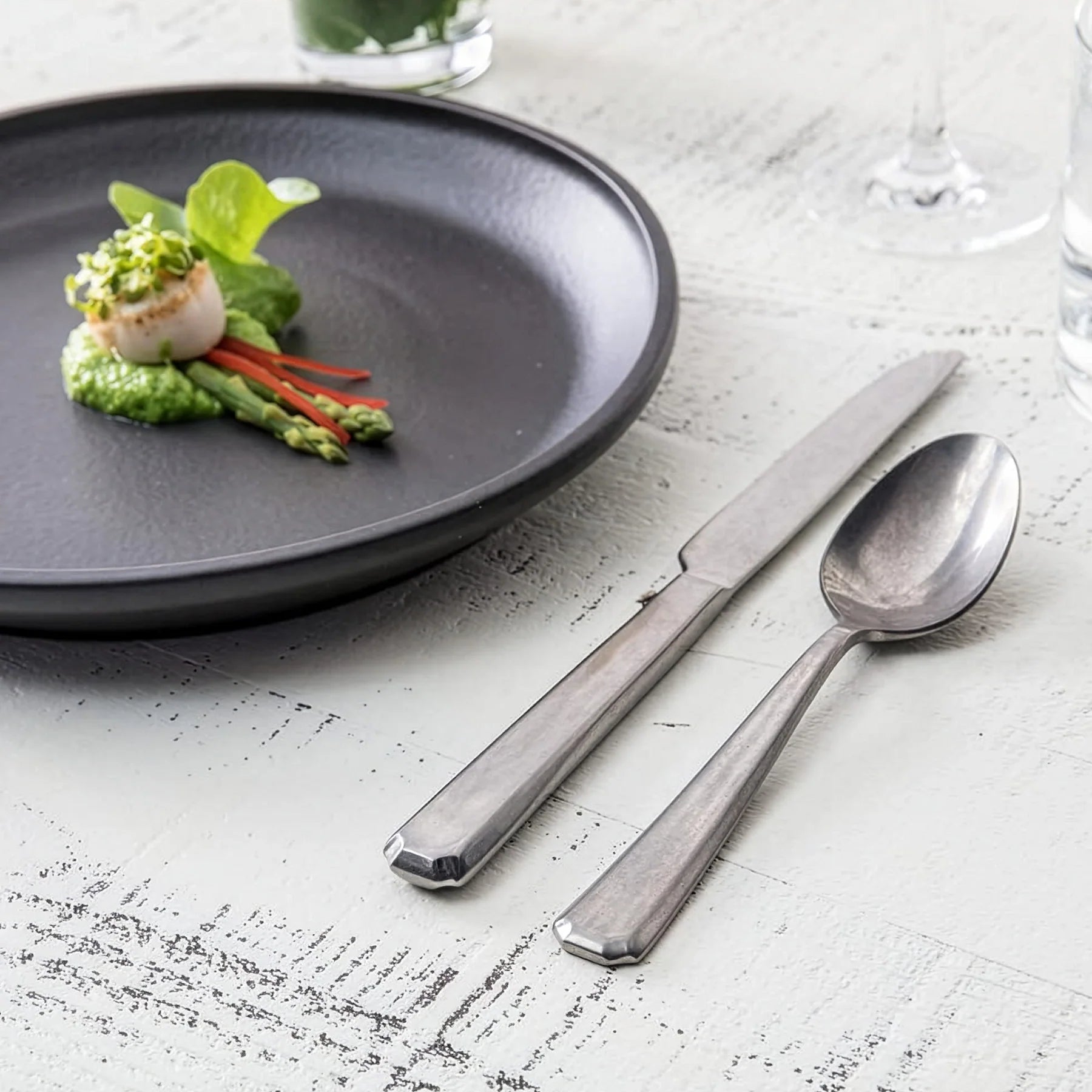 Montaje de mesa contemporáneo e industrial en el restaurante de un hotel boutique servido con la cubertería Valen Antiqued de Fortessa.