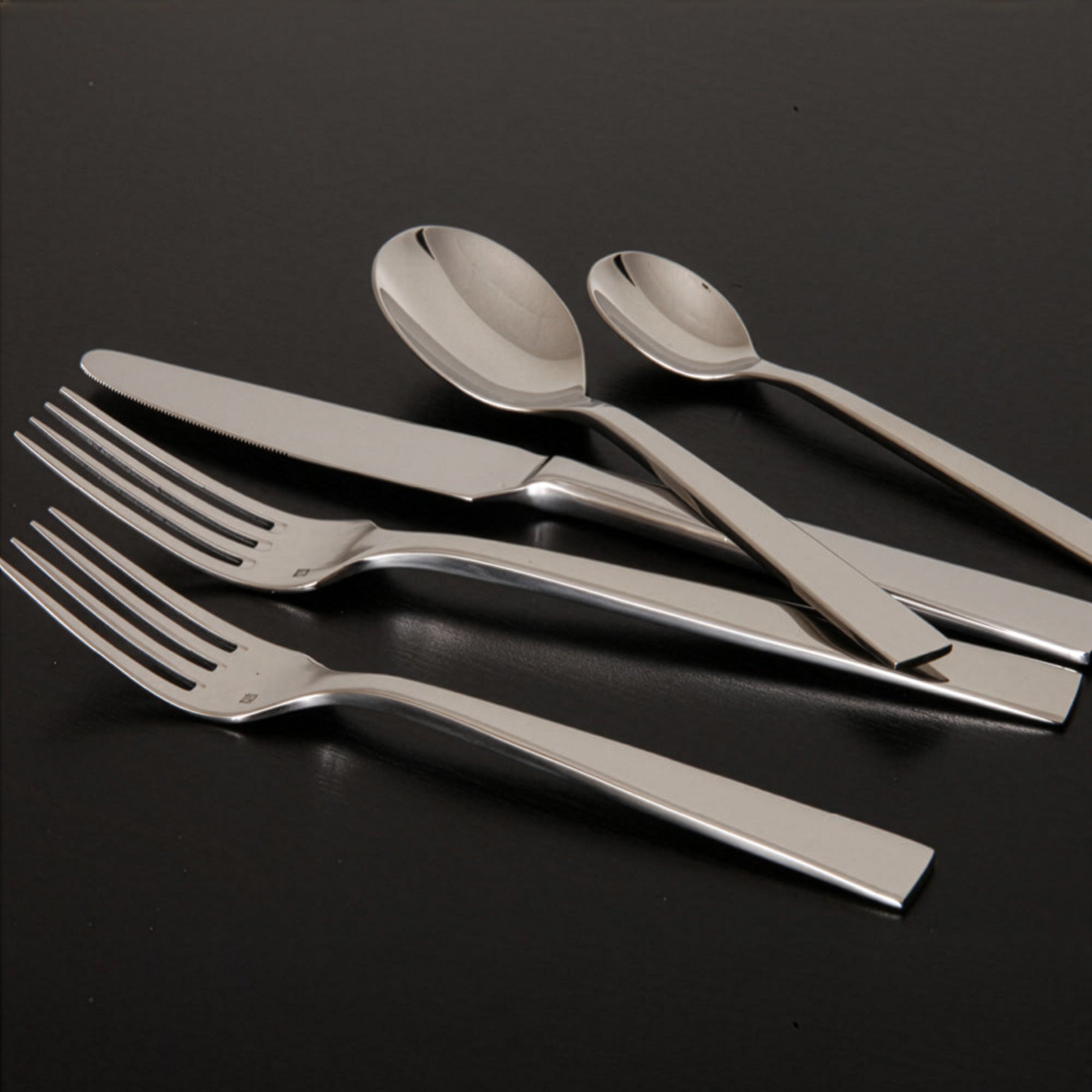 Set de cubiertos de gala de la colección Spada de Fortessa en acero inoxidable pulido espejo sobre un mantel blanco de lino.