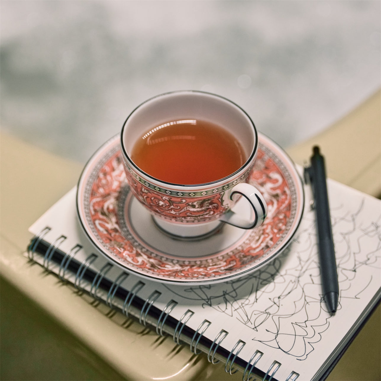 Primer plano de una taza de té de porcelana llena de té humeante con un plato a juego.