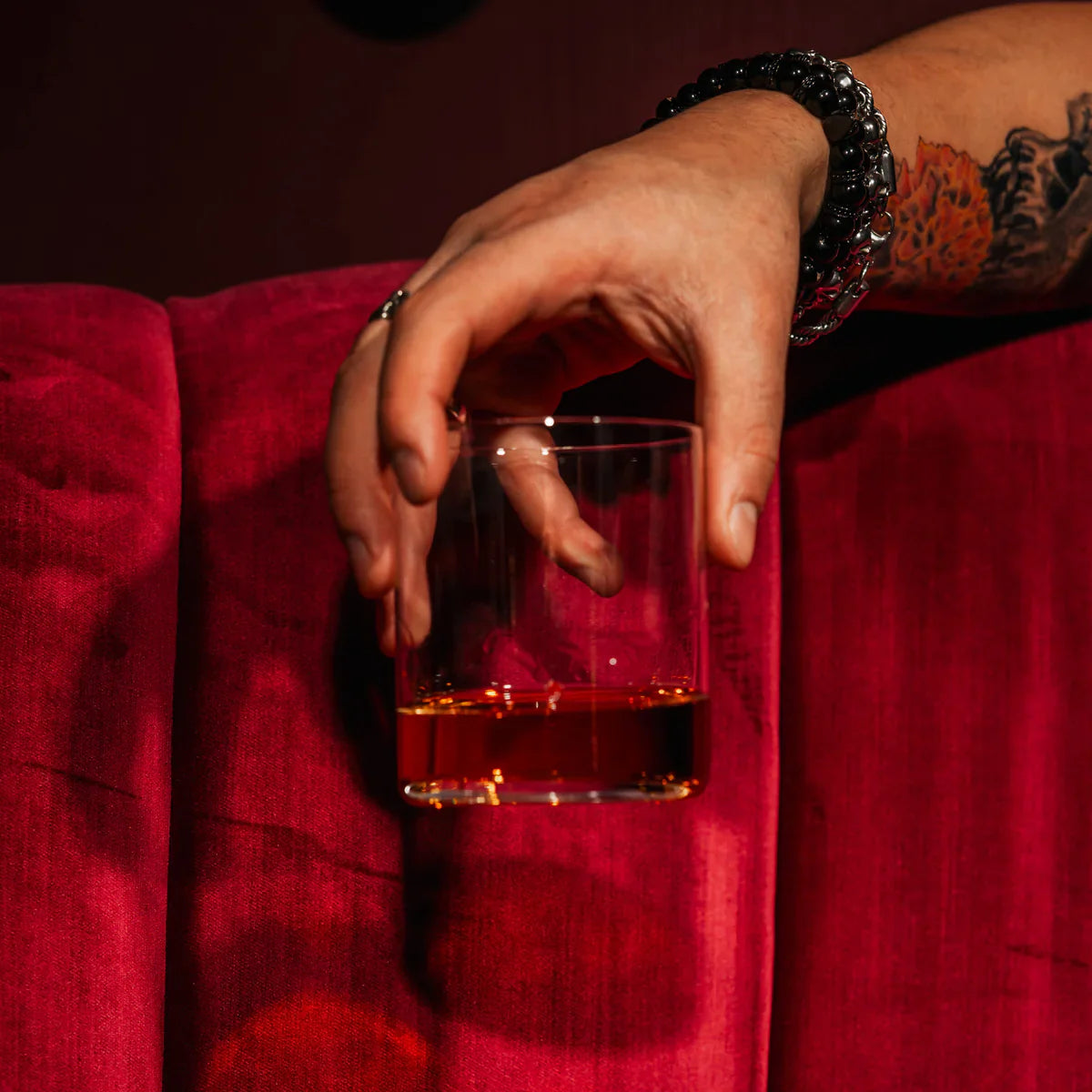 Vaso Whisky Kyoto de Stolzle Lausitz lleno de whisky, listo para degustar, con un fondo de bar acogedor.
