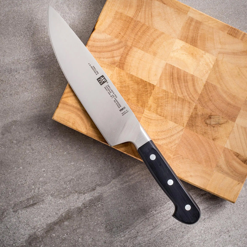 Cuchillo de chef profesional con mango ergonómico, sobre una tabla de cortar de bambú.