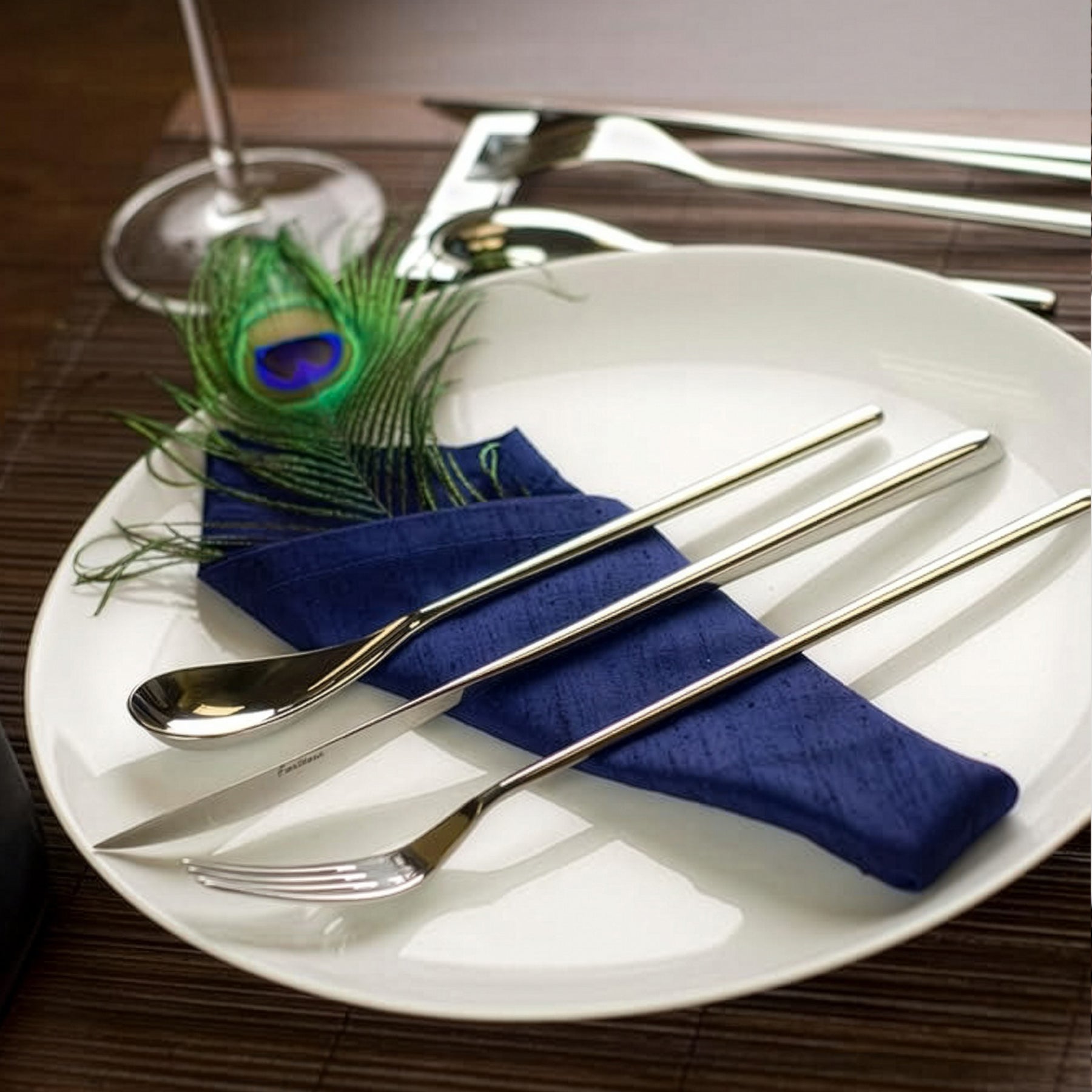 Set de cubiertos premium de la colección Dragonfly de Fortessa con silueta orgánica sobre un plato de alta cocina.