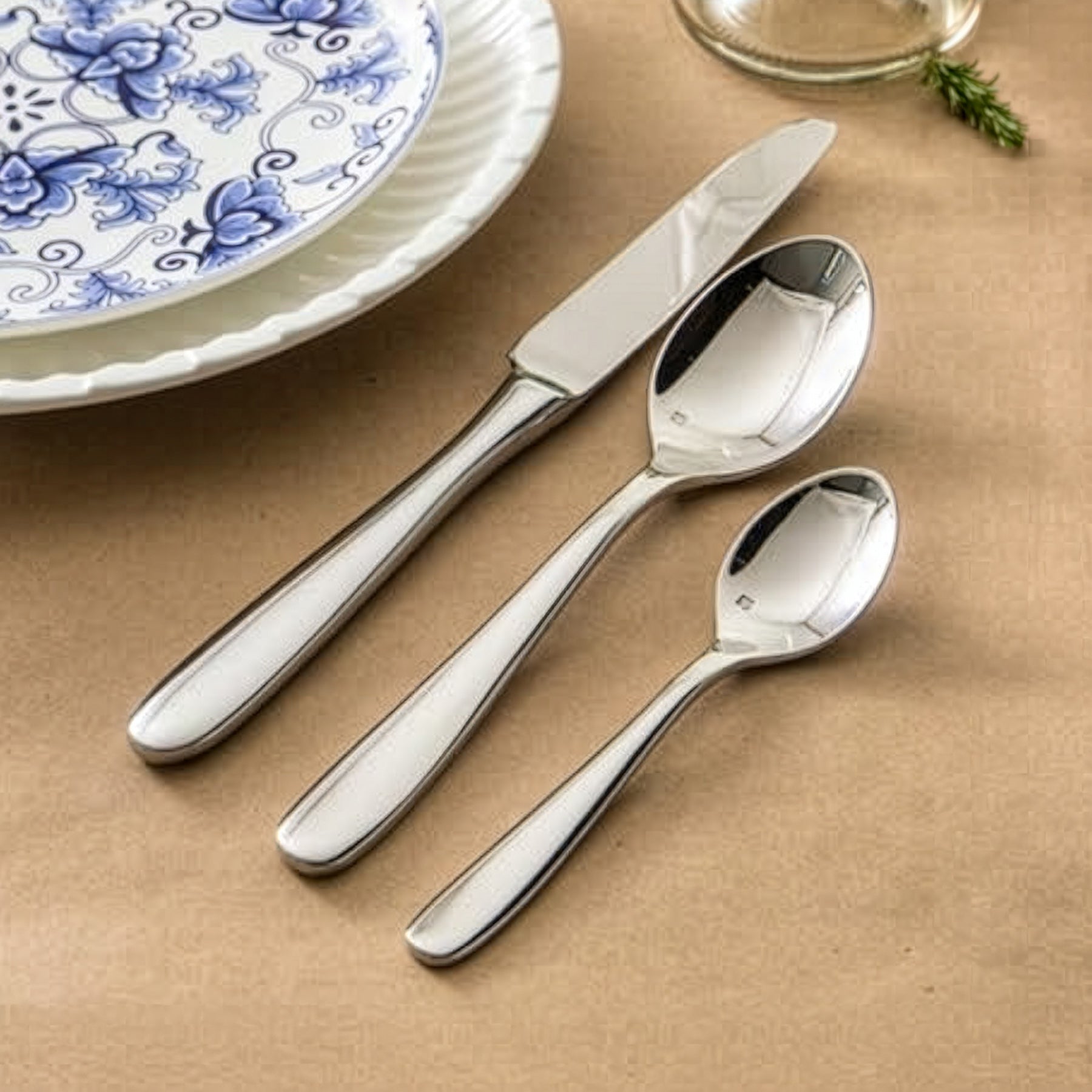 Set de cubiertos premium de la colección Grand City de Fortessa con diseño plano y pulido espejo sobre una mesa moderna.