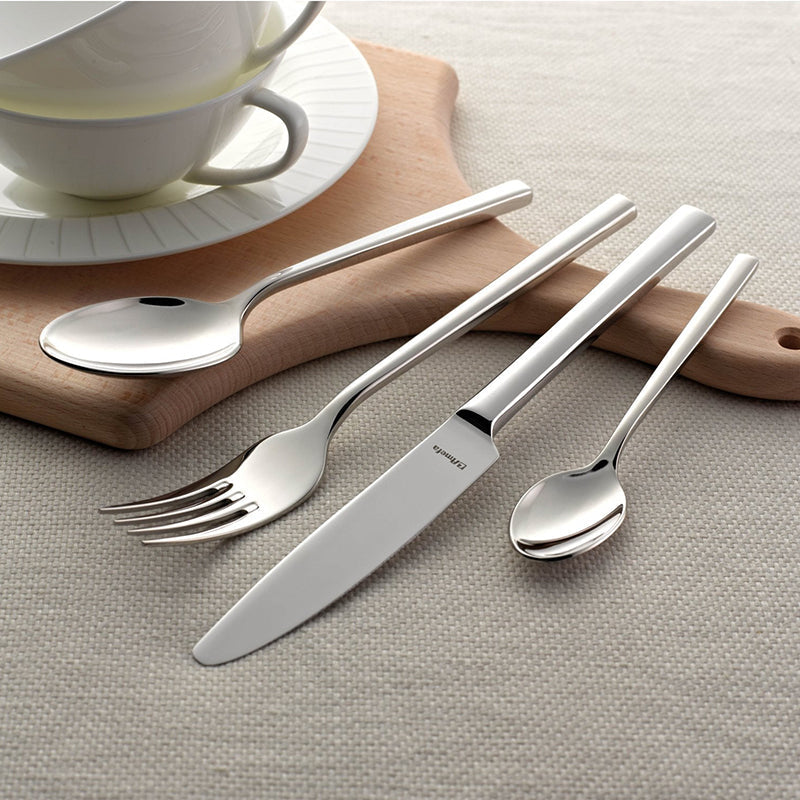 Set de cubiertos de acero inoxidable con acabado brillante, dispuestos sobre una tabla de madera.