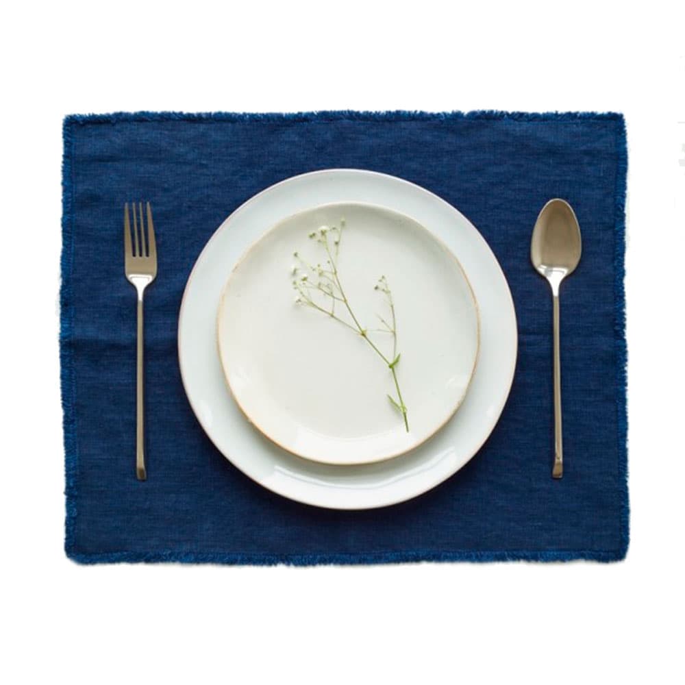 Primer plano de un individual en lino de linen tales con un plato de porcelana encima.