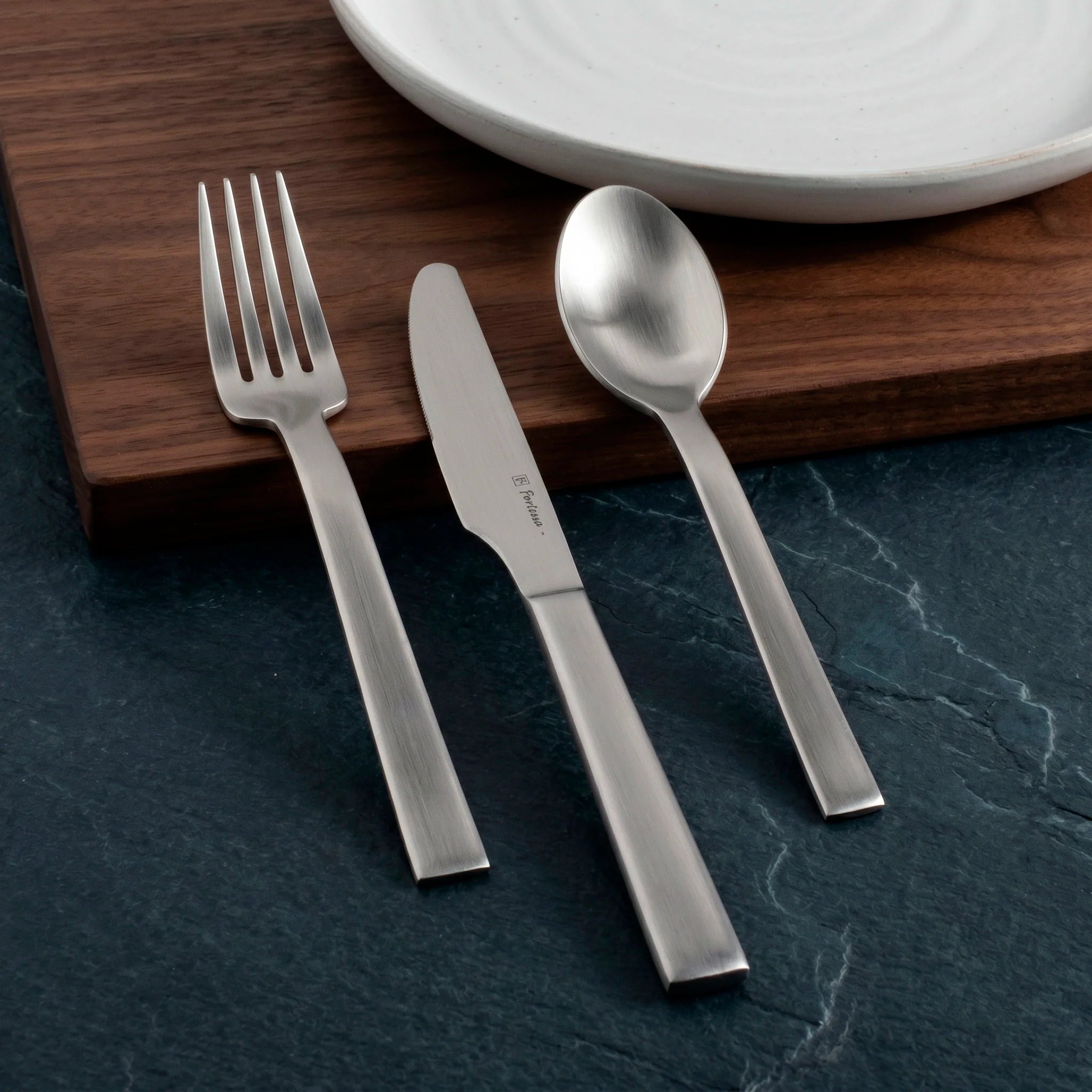 Montaje de mesa de estilo minimalista y zen en el restaurante de un hotel servido con la cubertería profesional Still Brushed de Fortessa.
